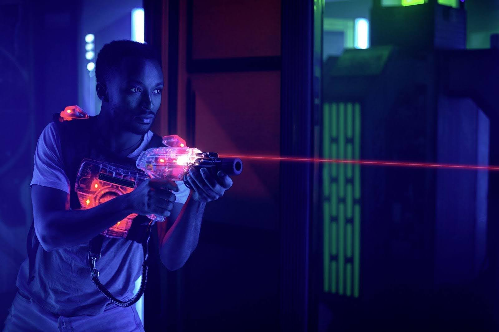 A man stands in a dark room holding a laser gun ready for action