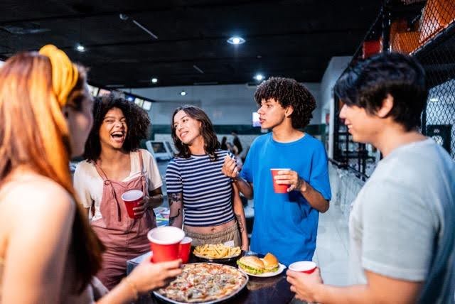 Friends chatting and laughing around a table with food and drinks