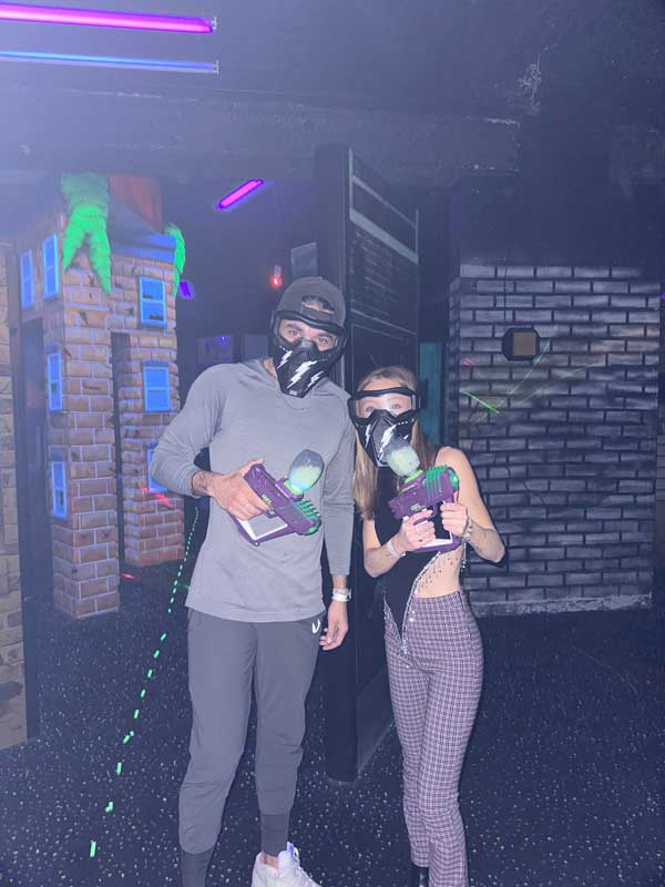 Two people wearing masks and holding a controller, playing video games together.