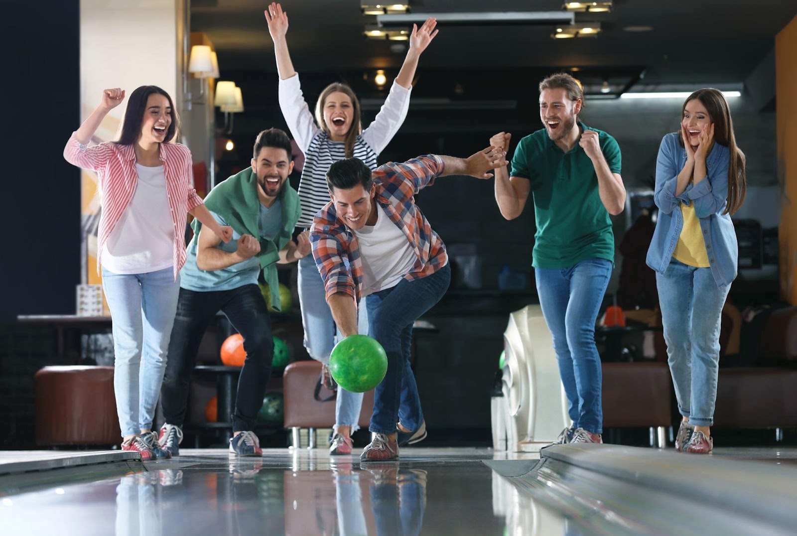 A diverse group of individuals enjoying a game of bowling at a bowling alley