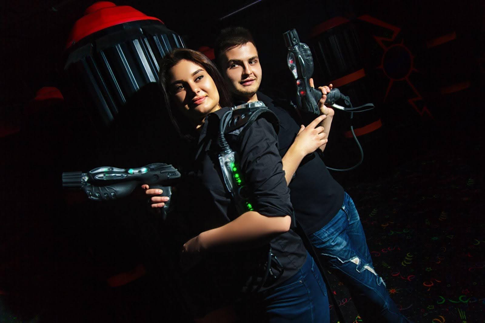 In a dark room, a man and woman grip guns indicating confrontation
