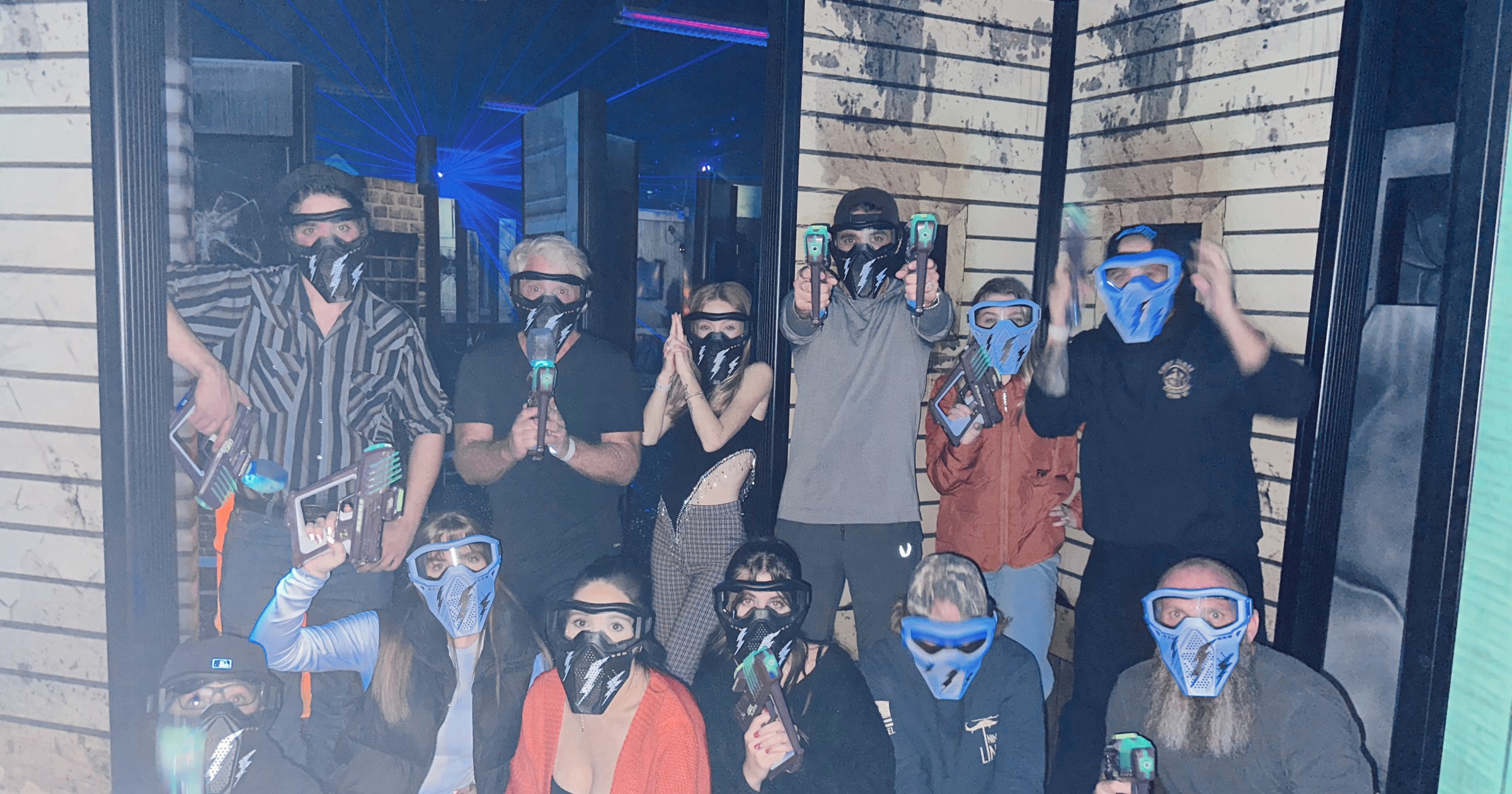 Company Christmas Party Ideas in Ogden Adult group in gel blaster masks posing together in the gel blaster arena at Skinny Dogz in Ogden