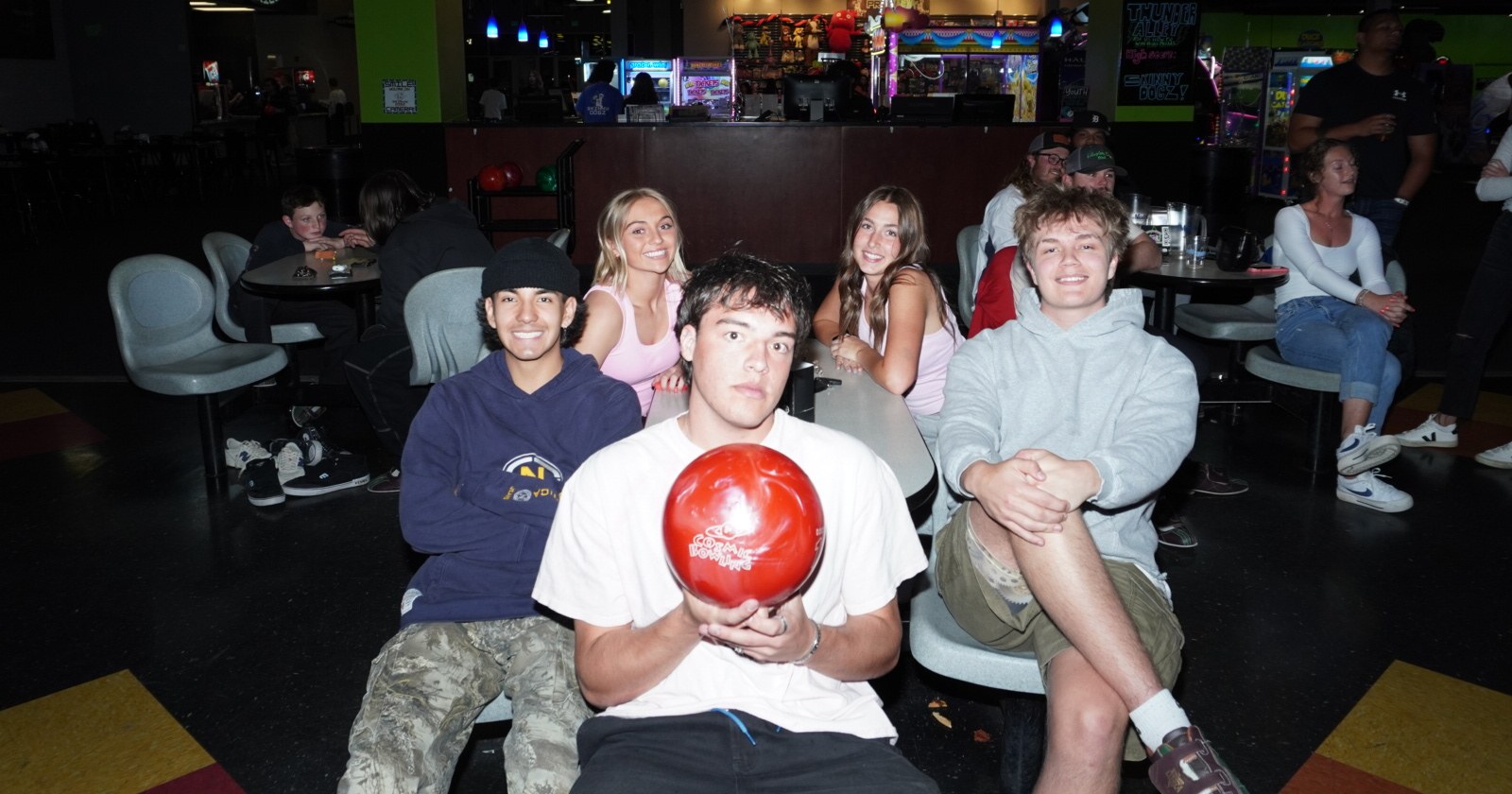 Group of teens gathered at the bowling lanes at Skinny Dogz in Ogden, one holding a red bowling ball